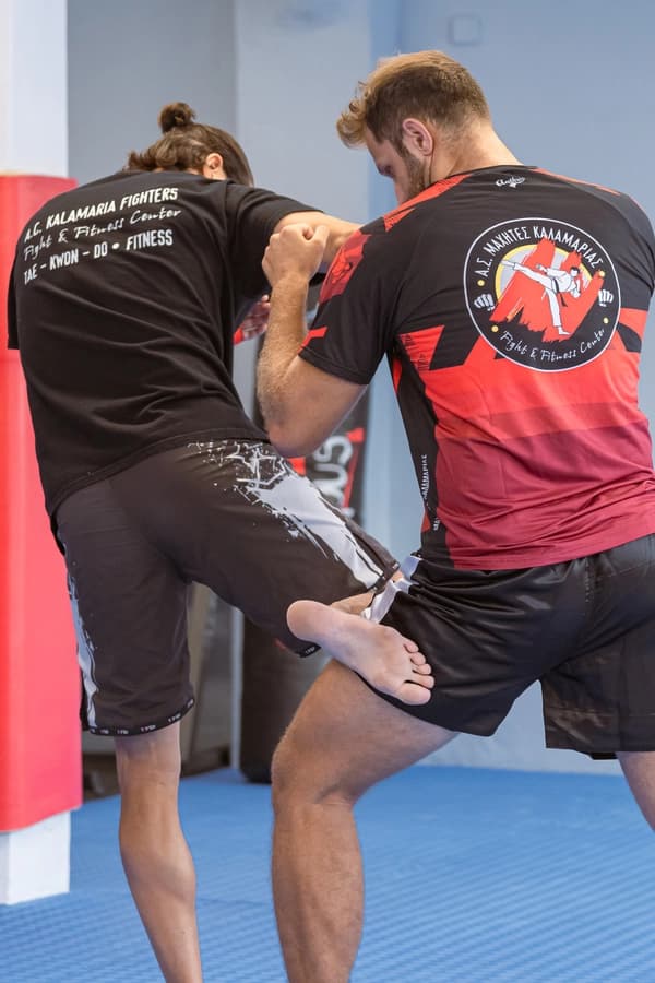 Δύο αθλητές αγωνίζονται, ο αριστερός κλωτσάει τον δεξίο και αυτός αμύνεται με το γόνατο του