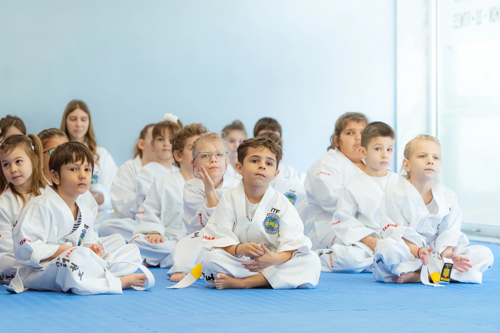 Μια σειρά από παιδιά που κάθονται οκλαδόν στο χώρο του αθλητικού συλλόγου